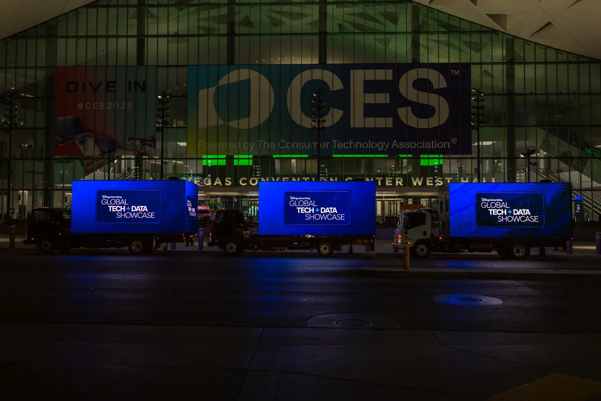 LED mobile billboard trucks displaying digital advertisements outside a major convention center at night